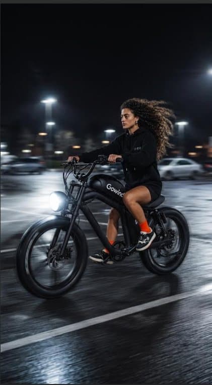 Mulher pilotando uma Gowind elétrica à noite, em um estacionamento molhado, com cabelo ao vento